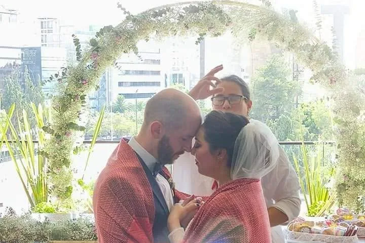 Pareja abrazada bajo un arco de flores en una boda tradicional mexicana